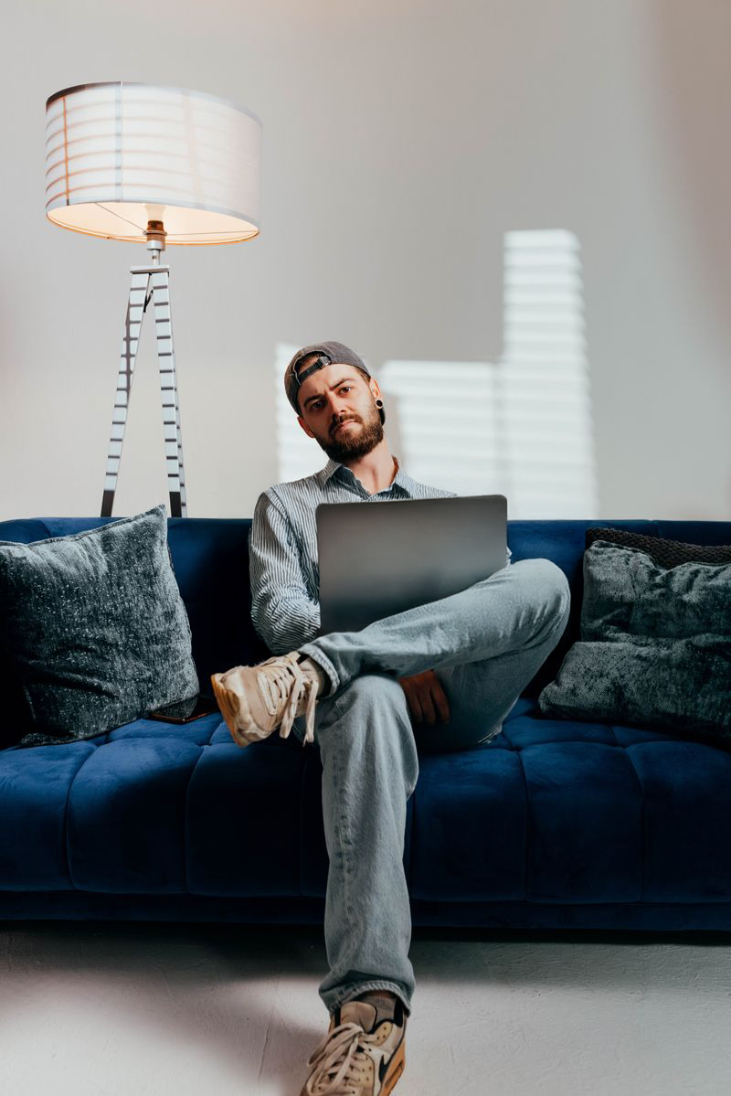 Martin Bruch mit Laptop auf einem blauen Sofa
